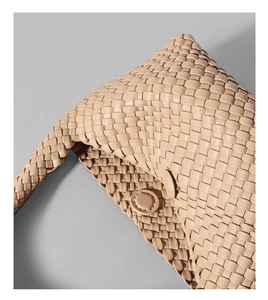Dettaglio ravvicinato di borsa a spalla in pelle intrecciata beige con fibbia rotonda