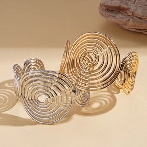 Exaggerated geometric spiral cuff bracelet in polished gold and silver metal tones