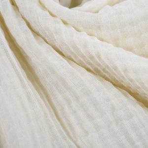 Close-up of beige crinkle fabric scarf showing soft cotton linen texture and gauze detail