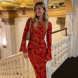 Detail of red floral bohemian maxi dress with bell sleeves on a marble staircase