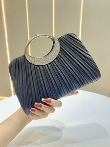 Detail of black pleated evening bag featuring a round metal handle with crystal rhinestones