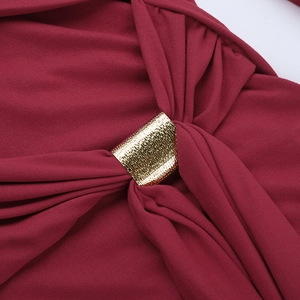 Gros plan sur une robe en maille bordeaux avec boucle décorative en métal doré