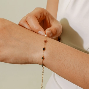 Close-up of bohemian gold bead bracelet with colorful stones worn on a model's wrist