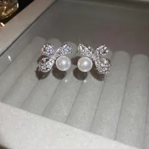 Elegant silver bow earrings with zircon diamonds and white pearls in a jewelry display box