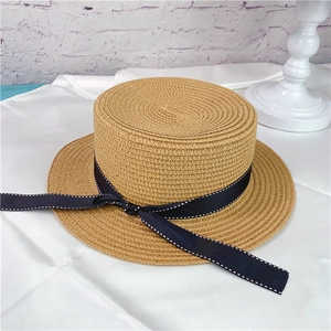 Detail of women's flat brim straw hat featuring black dotted ribbon and woven texture