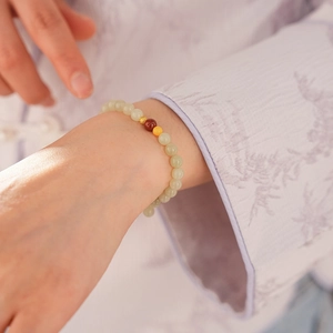 Close-up of retro style light green jade beads with gold hollow charm on woman's wrist
