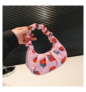Dettaglio della borsa a mano rosa increspata con stampe di fragole e manico a pieghe