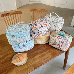 Gros plan de trousses de maquillage en coton matelassé aux motifs floraux et à carreaux