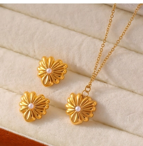 Makroaufnahme von Goldschmuckset mit Perlen und Herzblumen in weißer Box