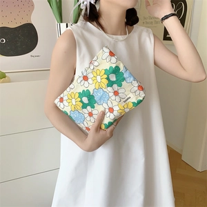 Macro shot of a floral cotton makeup bag with brand tag held in a lifestyle setting