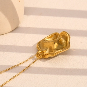 Detail of 18K gold plated flower necklace with pearl on a textured background