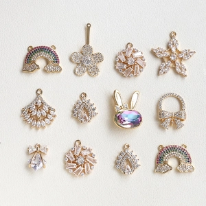 Detailed view of 12 gold plated charms with zircons including rabbit and flower motifs