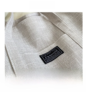 Close-up of beige woven canvas texture and black fashion label on women tote bag