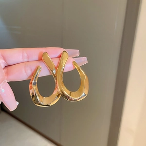 Close-up of golden irregular twisted geometric earrings with a polished metallic finish