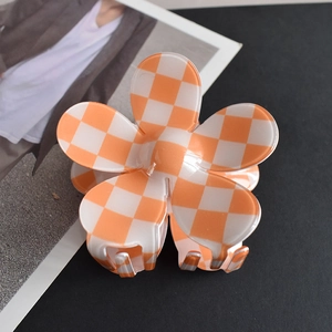 Close-up of orange and white checkerboard flower hair claw clip on fashion magazine