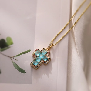 Detailed close-up of a gold cross pendant featuring colorful zircon stones on a box chain