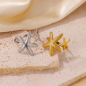 Anelli a stella marina in acciaio inox oro e argento su sfondo di pietra naturale