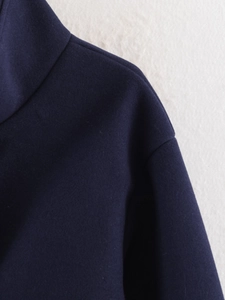 Detailed close-up of dark blue wool coat neckline with high-quality stitching and texture