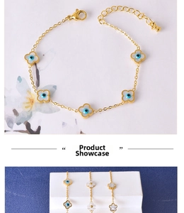 Close-up of golden stainless steel bracelet with blue evil eye and flower shell charms