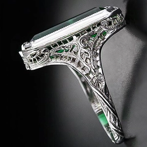 Detail view of large emerald green rectangular stone with intricate silver filigree band
