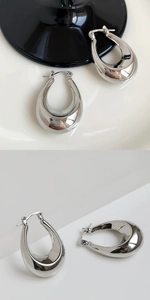 Detailed close-up of polished silver U-shape earrings with a smooth mirror finish