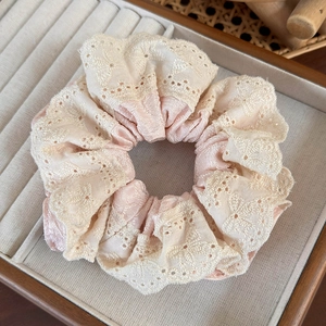 Detail of beige lace and pink satin fabric hair scrunchie in a soft velvet display tray