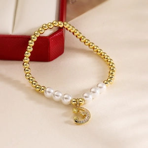 Close-up of gold beaded bracelet with pearls and zircon-inlaid star and moon charm