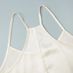 Close-up of ivory satin mini dress showing fine fabric texture and strap detail