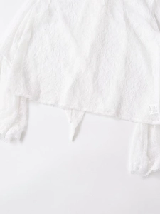 Close-up of white lace fabric detailing delicate hollow patterns on the sleeve hem