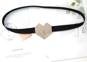 Close-up of a heart-shaped buckle with sparkling rhinestones on a black elastic belt