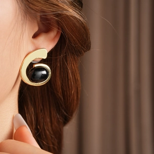 Gros plan d'une boucle d'oreille dorée chiffre six avec une pierre noire sur un mannequin