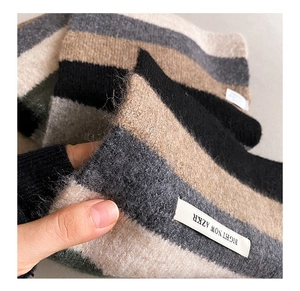 Close-up of soft mohair striped scarf texture showing gray and beige wool blend fabric