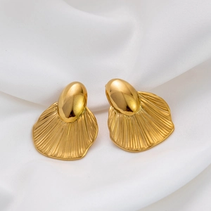 Macro shot of 18K gold plated titanium fan-shaped earrings on elegant white silk fabric