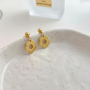 Elegant gold flower drop earrings with five-petal design on white ceramic tray