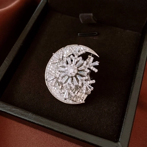 Detailed view of silver crescent moon and snowflake brooch on black velvet gift box
