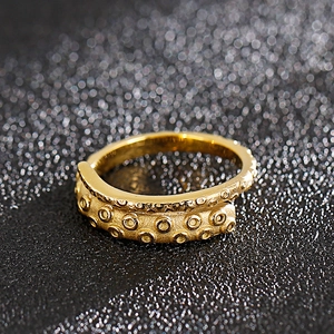 Detailed macro view of the gold octopus tentacle texture on a retro steel ring