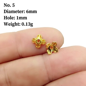 Macro view of a 6mm golden flower bead cap spacer held between fingers for size reference