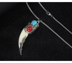Close-up of wolf tooth necklace with inlaid red gemstone and blue turquoise pendant