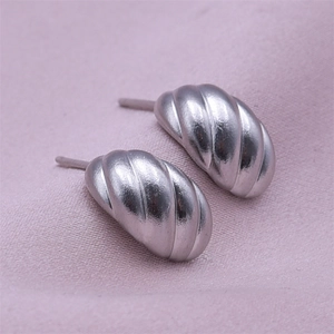 Macro shot of silver croissant stud earrings with brushed texture on purple velvet