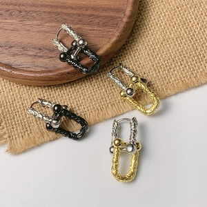 Close-up of U-shaped punk earrings with cable texture and metal beads on wood