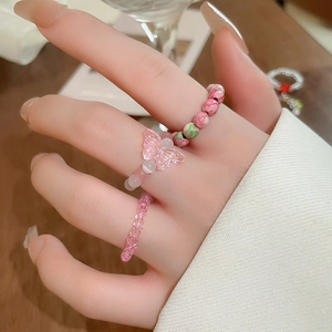 Detailed view of pink butterfly beaded elastic rings worn on hand for a sweet aesthetic
