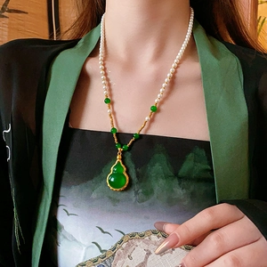 Détail du collier plaqué or avec pendentif gourde verte et perles blanches sur modèle