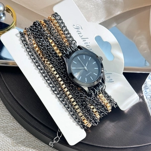 Close-up of stylish black and gold multi-layer chain strap quartz watch on jewelry card