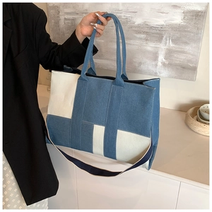 Detail of blue and white patchwork denim tote bag showing handles and shoulder strap texture