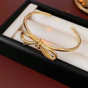 Macro di un bracciale rigido a fiocco dorato con finitura metallica su scatola regalo