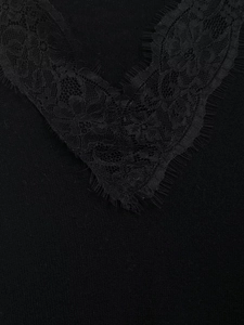 Close-up of elegant black V-neckline with delicate eyelash lace trim and knit fabric