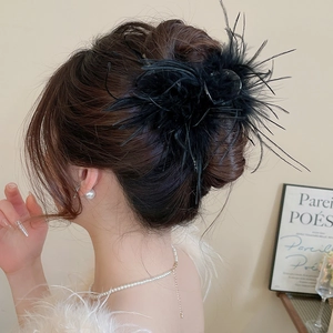 Detailed view of elegant black feather hair claw clip styled on a classic bun hairstyle