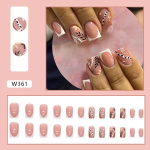 French tip press-on nails with white leaf silhouettes and gold glitter accents