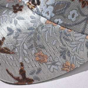 Detailed close-up of floral embroidery on silver baseball cap with reinforced stitching