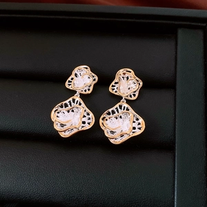 Detailed macro of bicolor gold and silver rose earrings on a black leather jewelry display